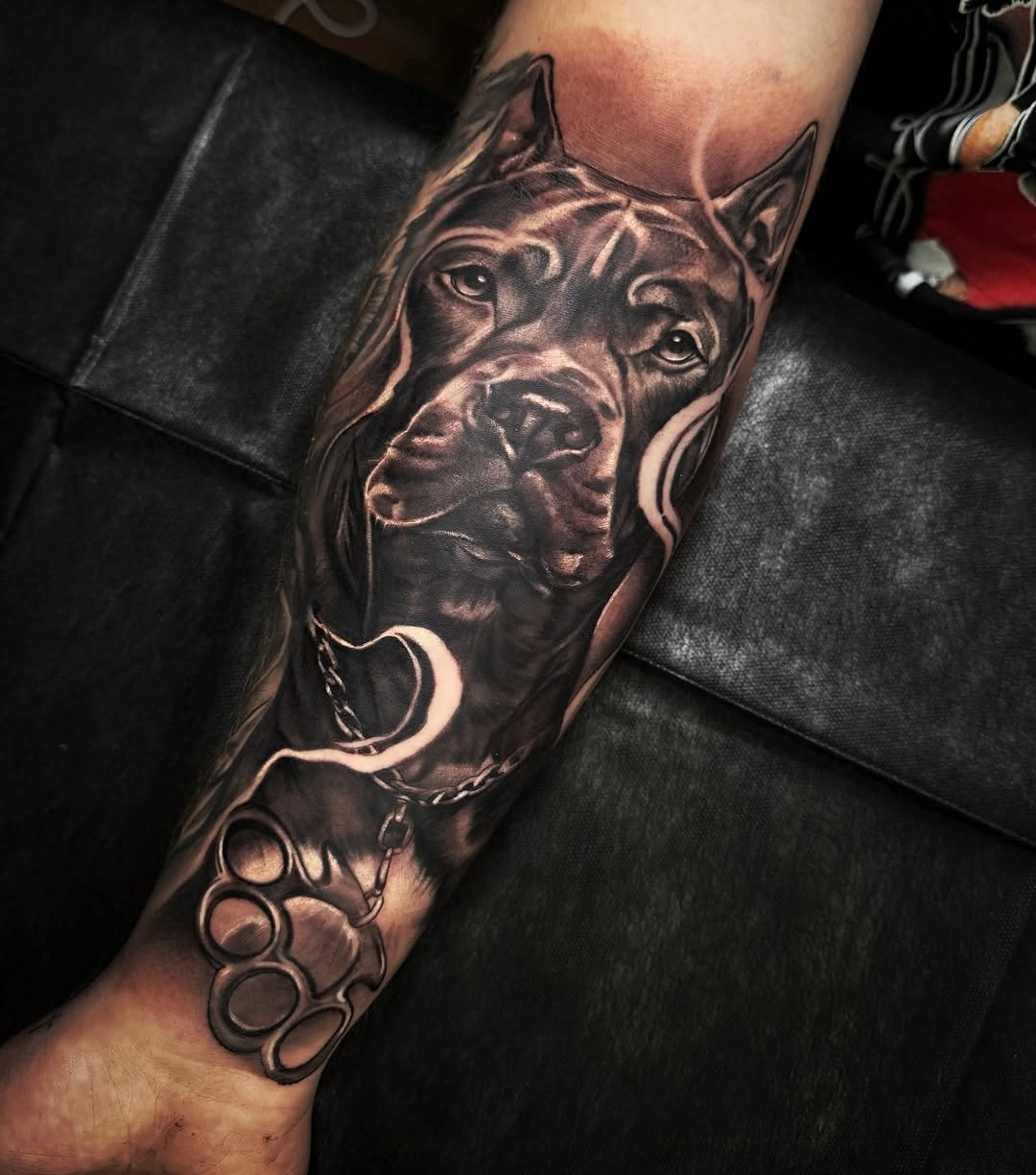 Hyper-realistic black-and-gray pitbull head with chain on calf