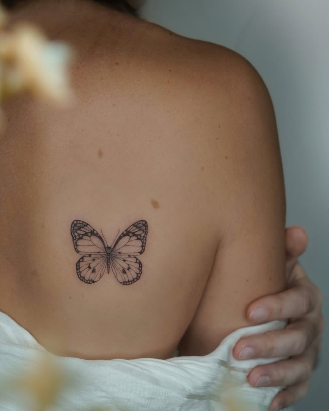Delicate black butterfly with fine-line detailing.