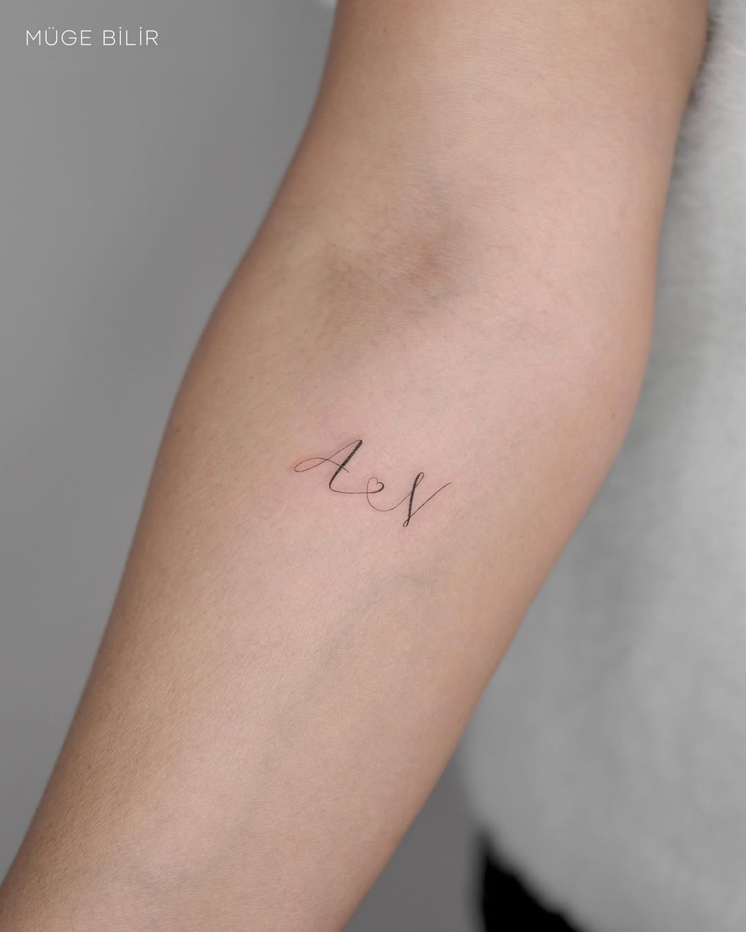 Delicate cursive initials AEN on inner forearm
