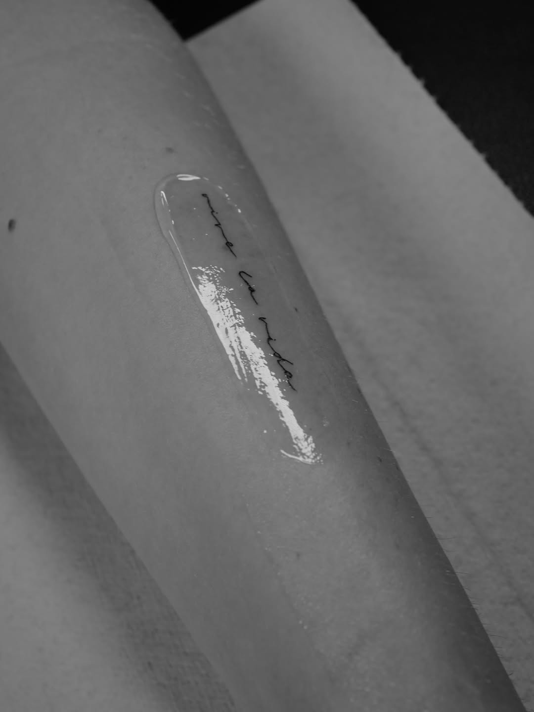 Delicate cursive script tattoo with a glossy highlight