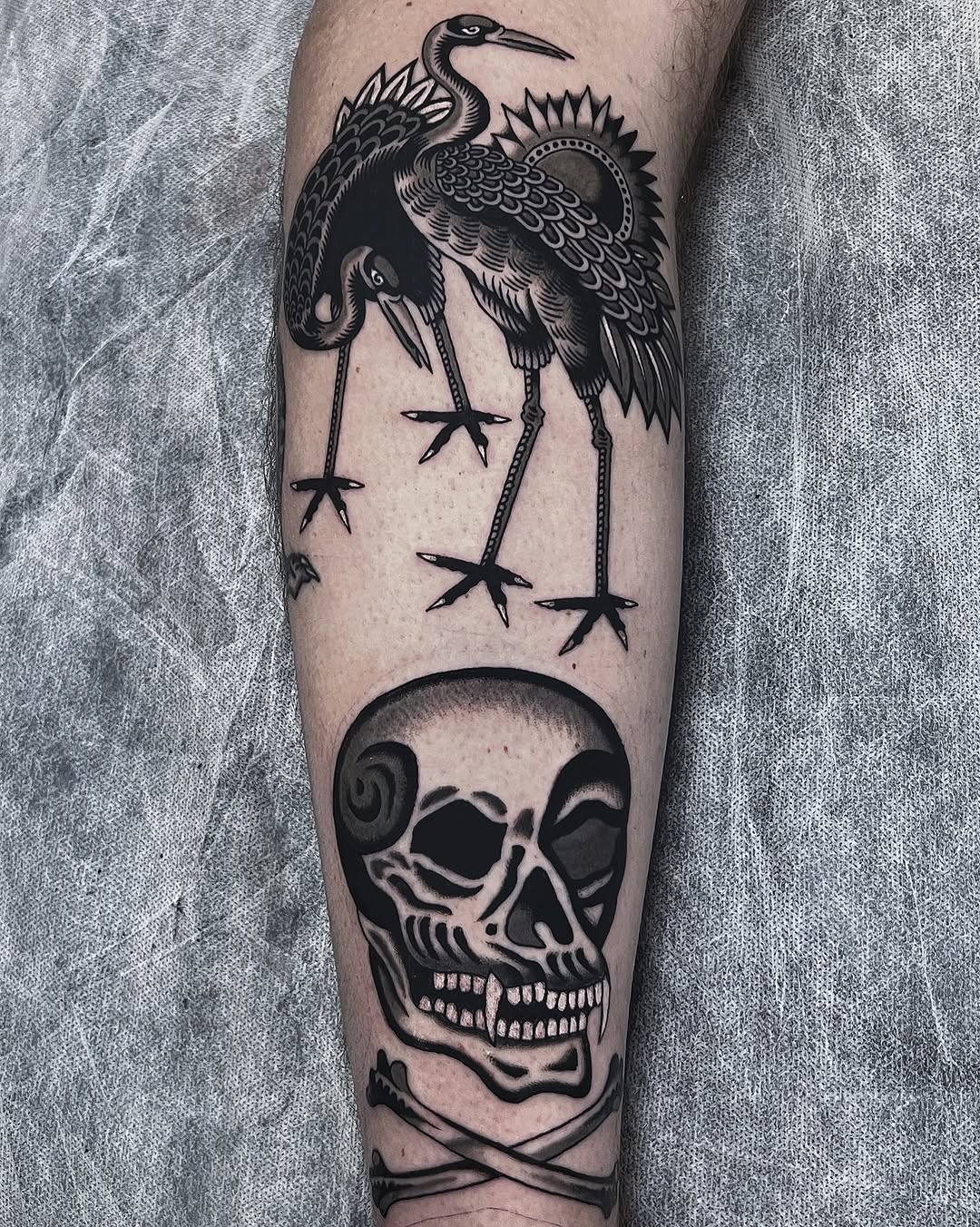 Bold blackwork crane with long legs above a grinning skull