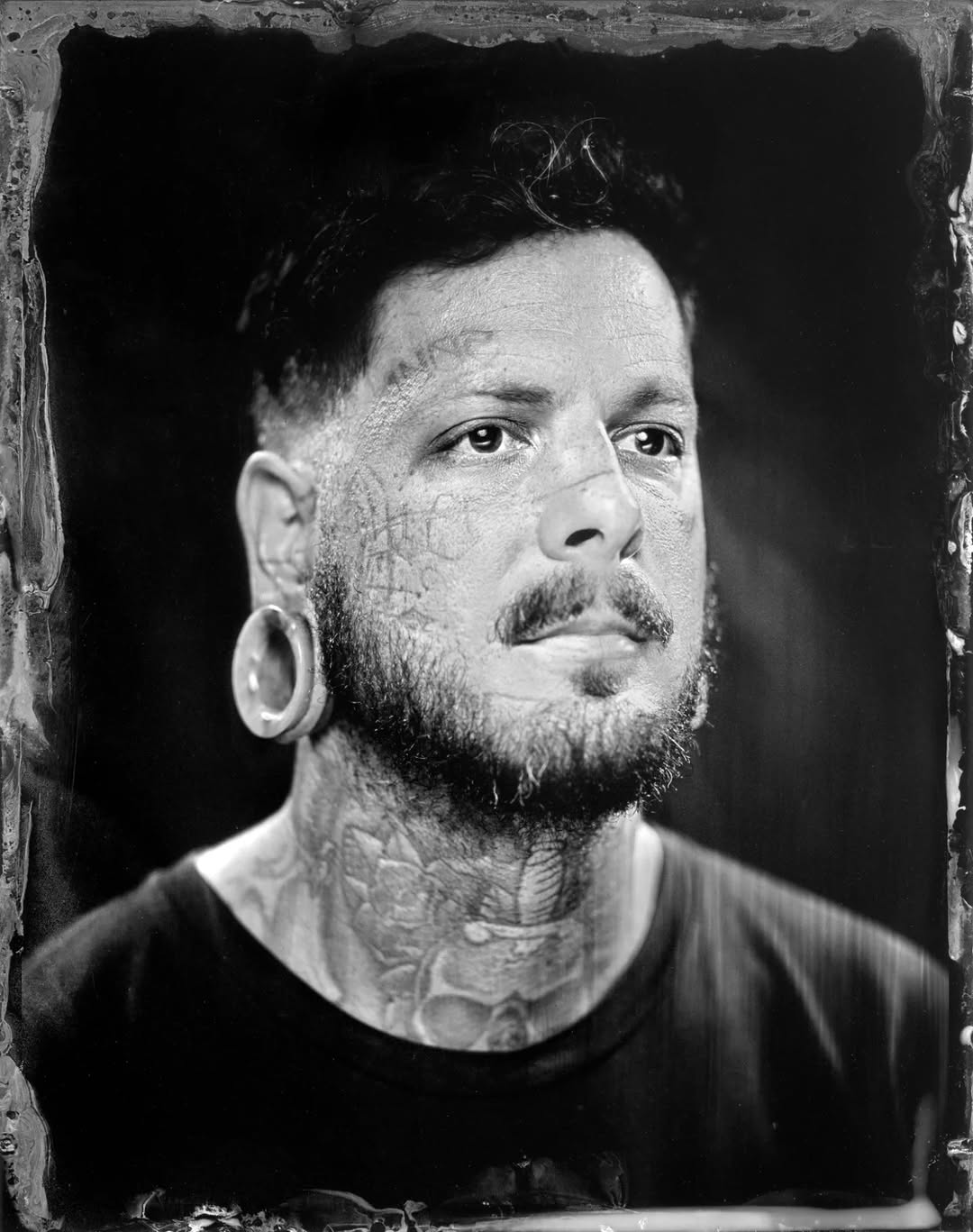 High-contrast black-and-gray neck and facial tattoos portrait