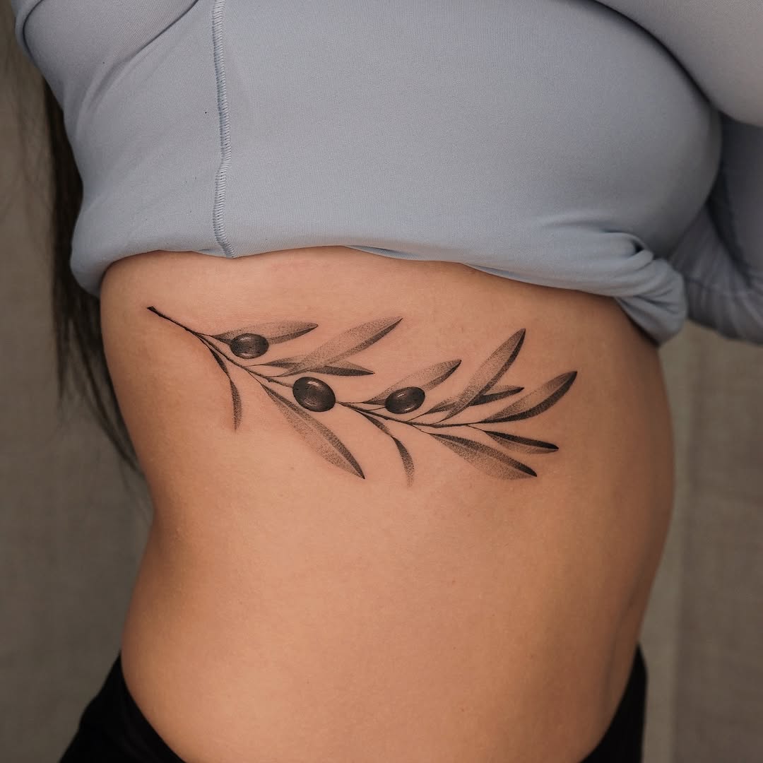 Elegant olive-branch tattoo with bold berries and fine shading