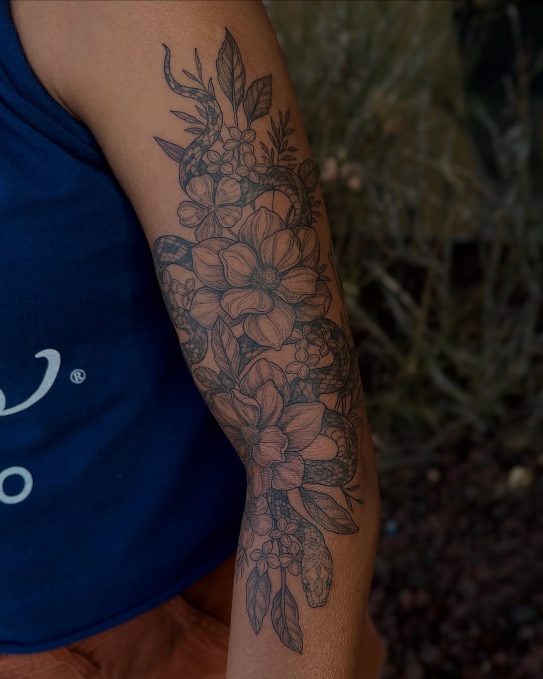 Intricate floral sleeve with magnolias and a coiled snake