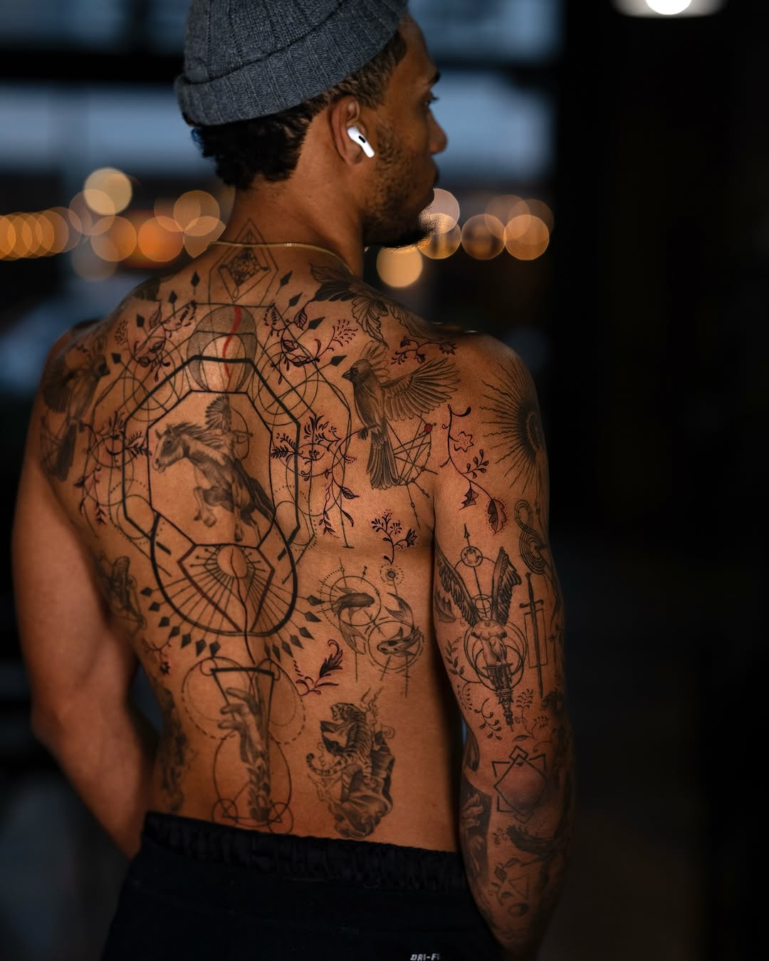 Intricate blackwork back piece weaving geometric lattice and fauna