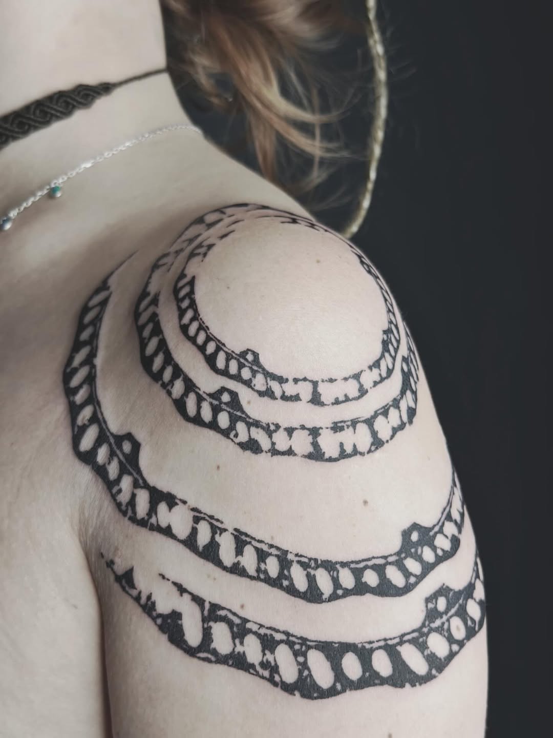 Bold black ornamental coils wrap shoulder in rings