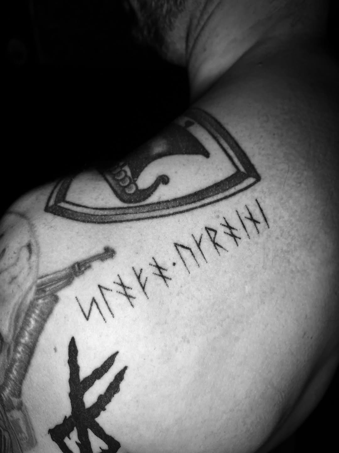 Healed rune row in bold black linework along shoulder