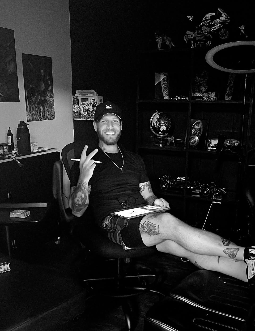 Chill tattoo artist posing confidently with leg tattoos visible.