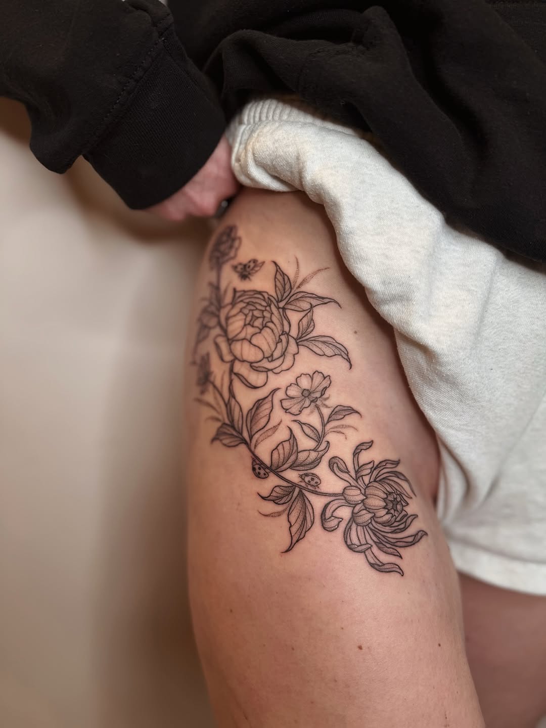 Delicate botanical forearm florals with tiny ladybug accent
