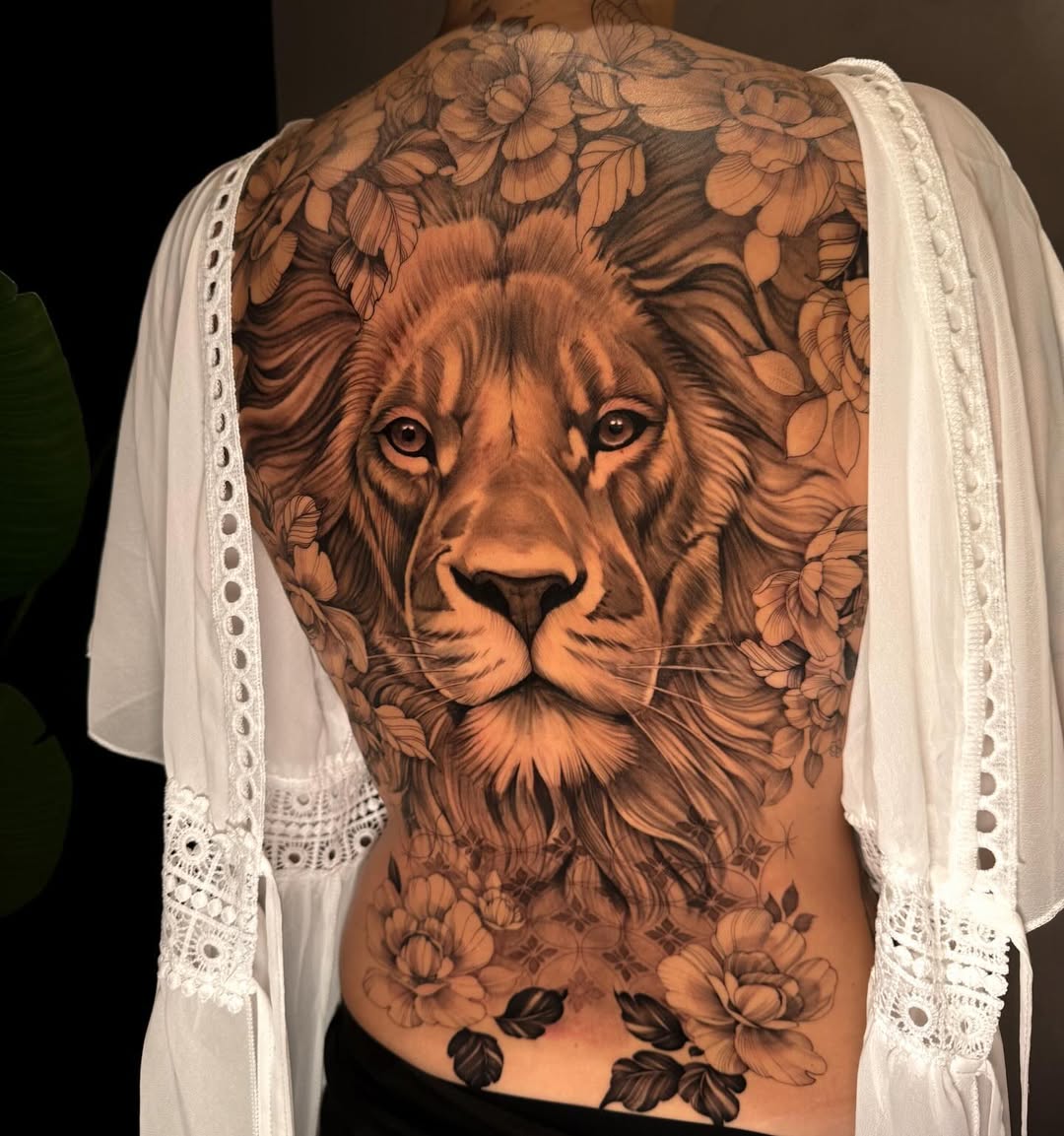 Monumental black-and-gray lion head framed by blossoms on back.