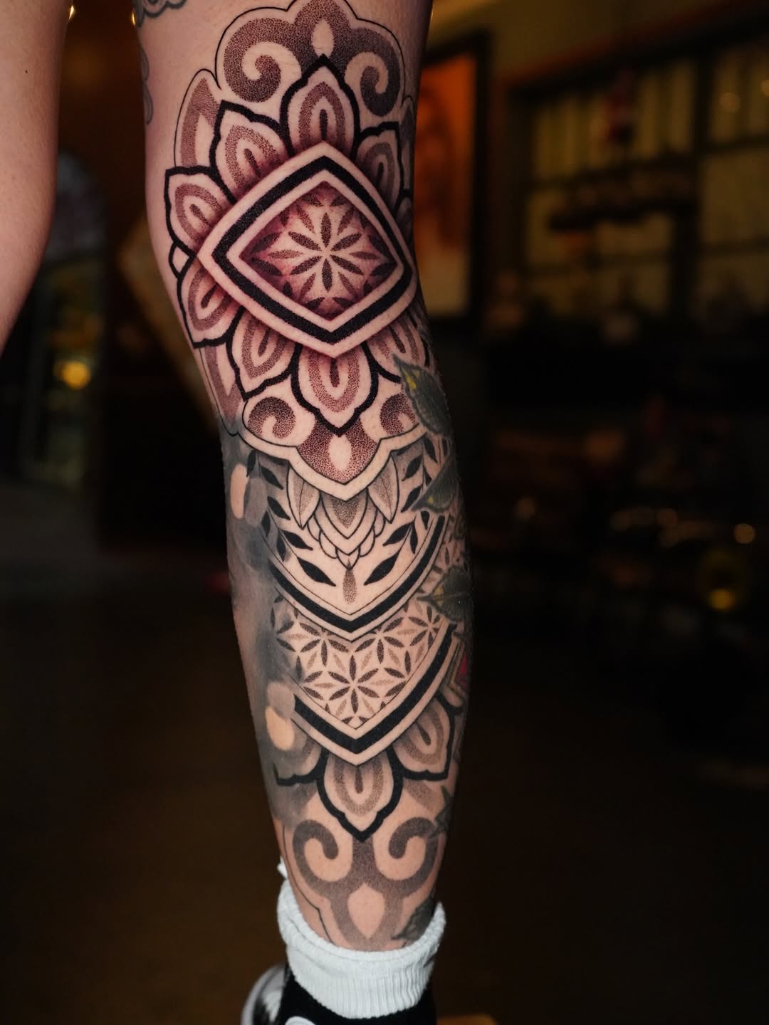 Intricate blackwork geometric mandala leg tattoo with bold outlines