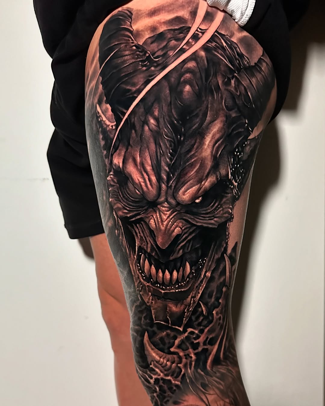 Dark, menacing demon face leg sleeve in grayscale.