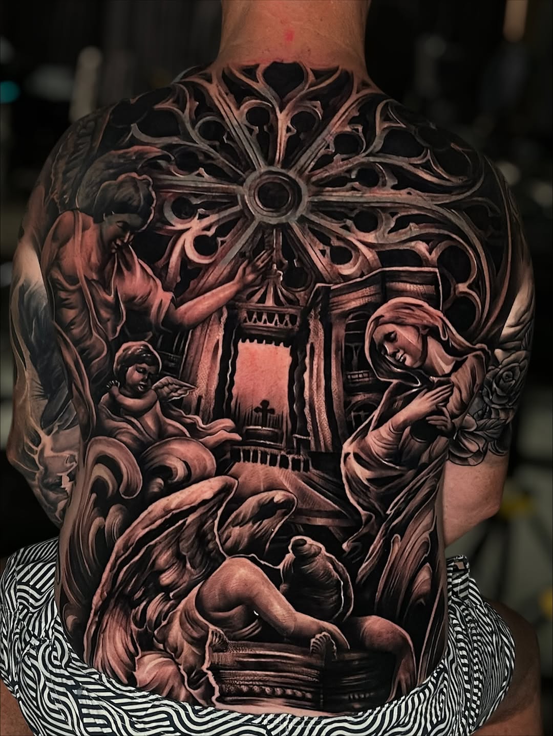 Intricate black-and-gray back piece with cathedral arches, angels