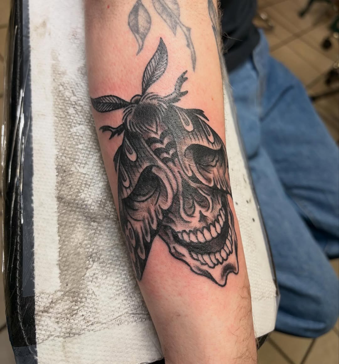Bold blackwork skull with dramatic shading and moth motif