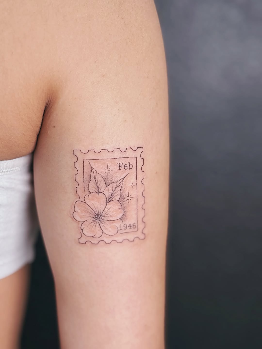 Delicate postage-stamp floral tattoo marking February bloom.