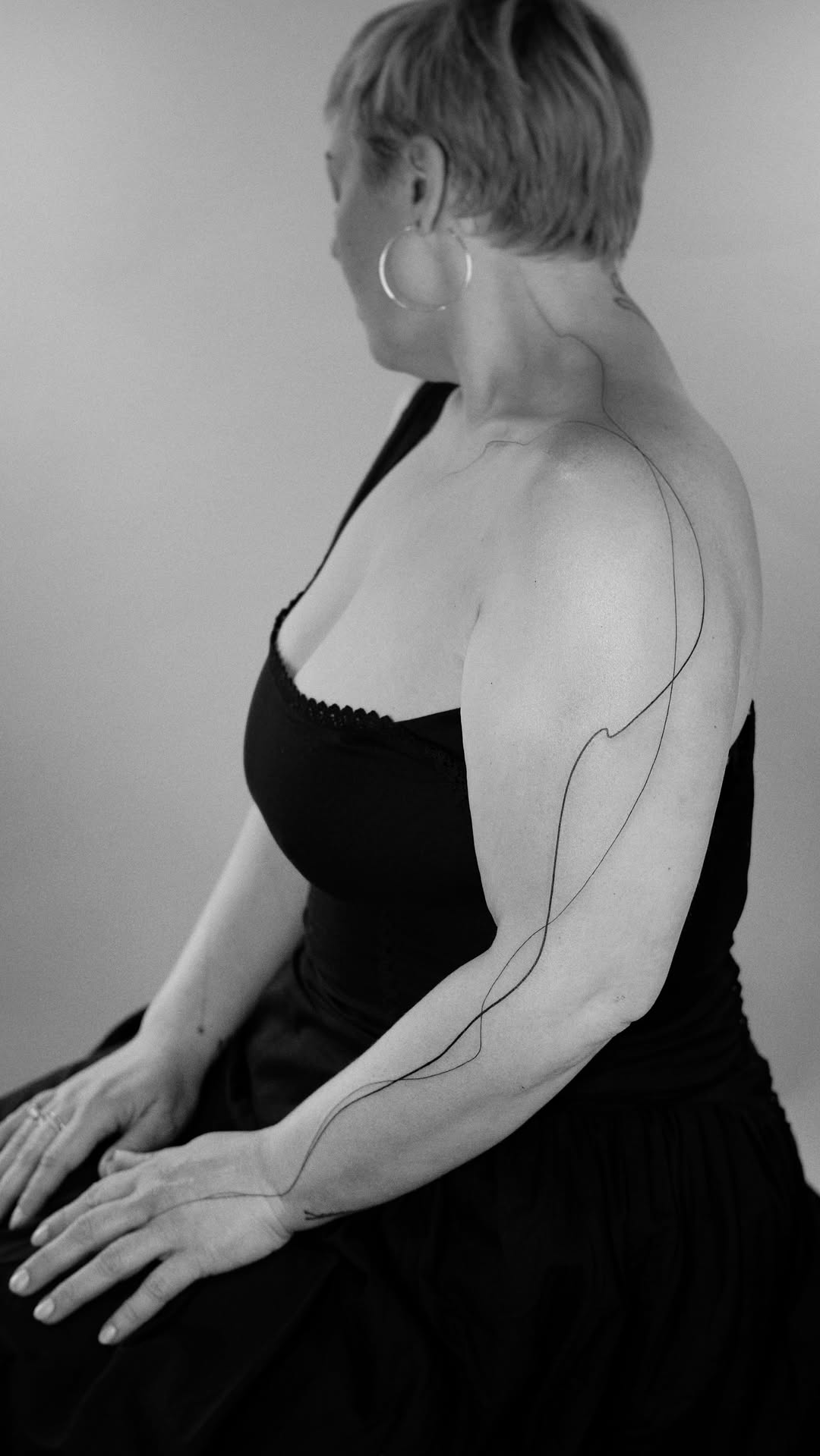 Elegant single-line tattoo tracing shoulder to forearm.