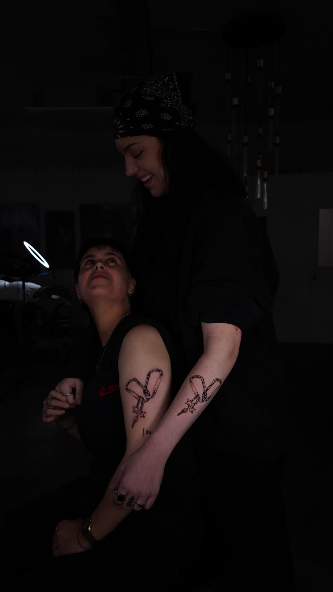 Matching fine-line carabiner tattoos with dangling star charms