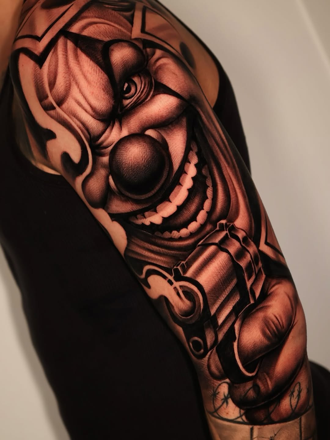 Hyper-detailed grayscale clown portrait on upper arm.