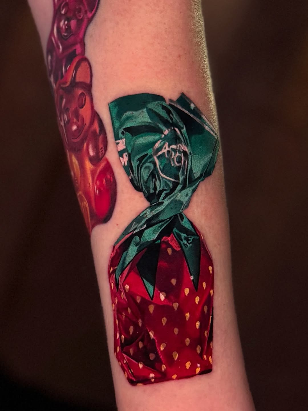 Vibrant strawberry tattoo wrapped in teal origami ribbons