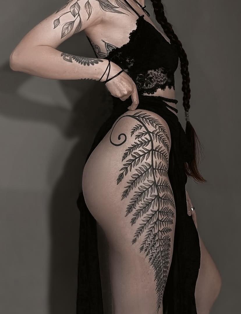 Elegant fern fronds wrap the thigh in blackwork.