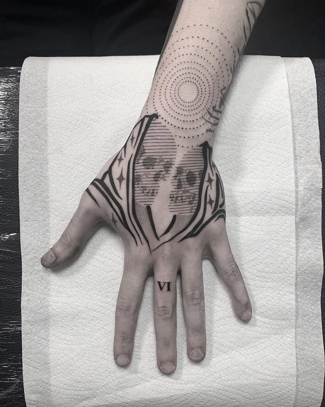 Concentric dotwork spirals meet bold geometric blackwork on hand and forearm.