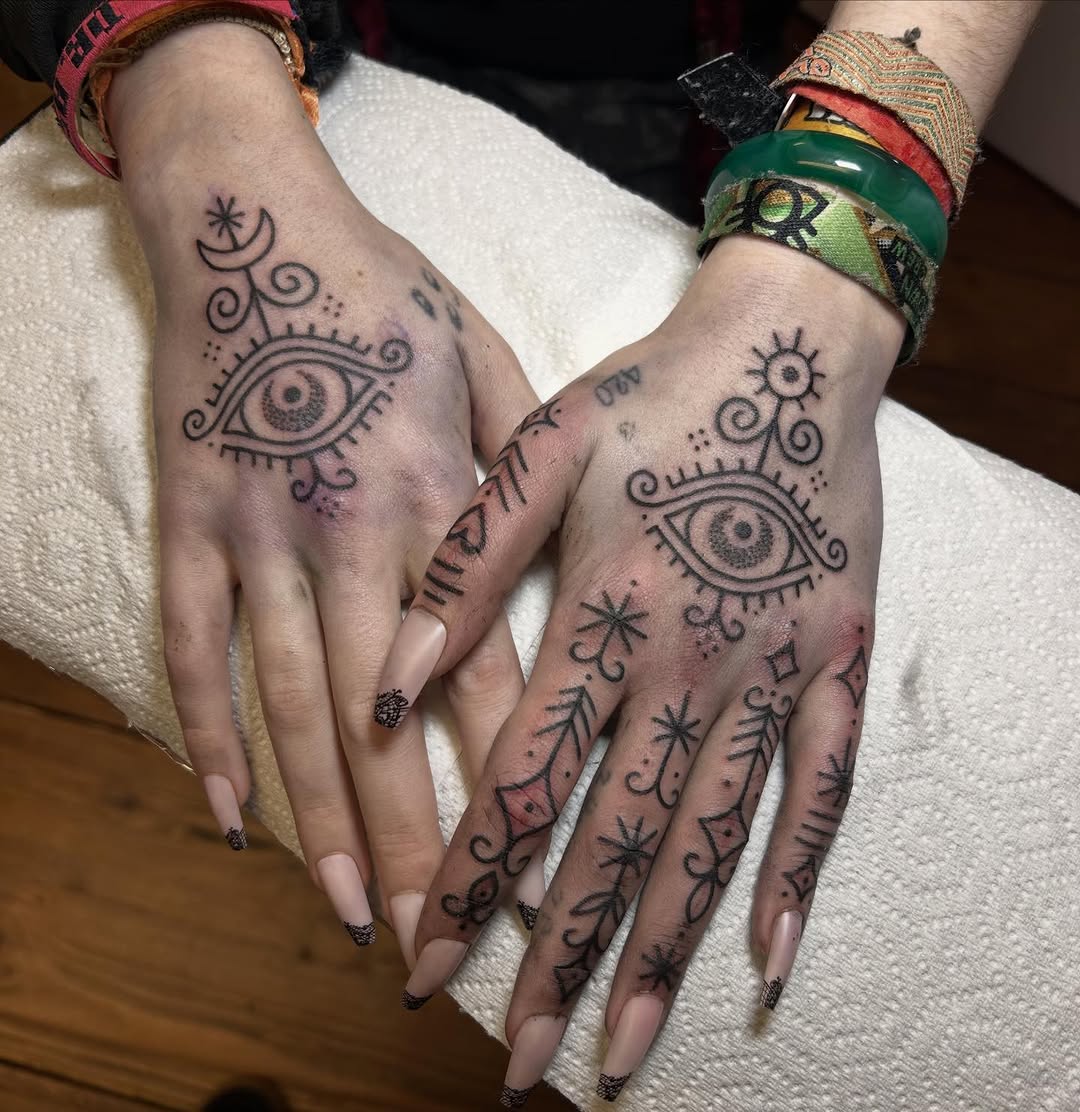 Intricate black-line eye motifs with ornamental swirls across hands