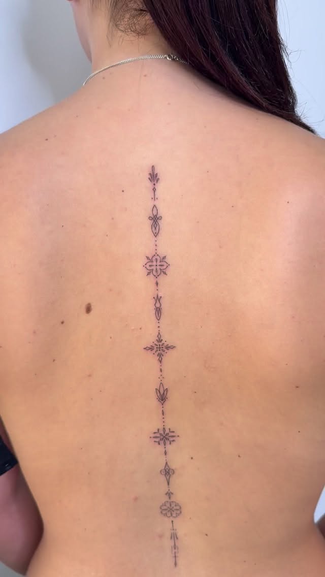 Delicate fine-line spine ornament with graceful vertical symmetry