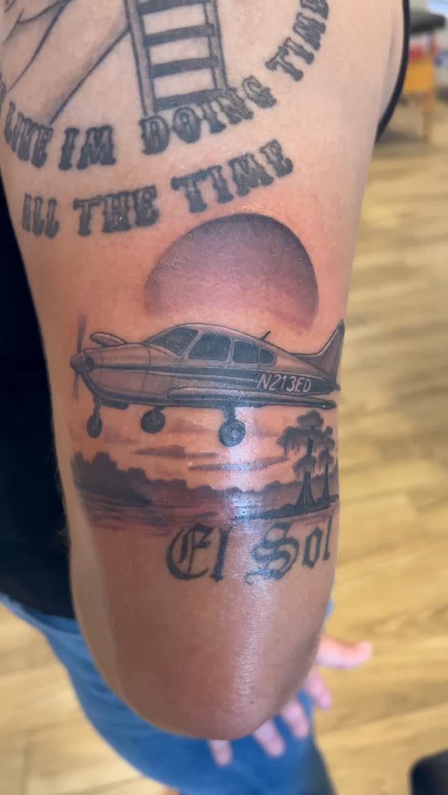 Somber memorial scene: sunset, palm trees, and a small prop plane