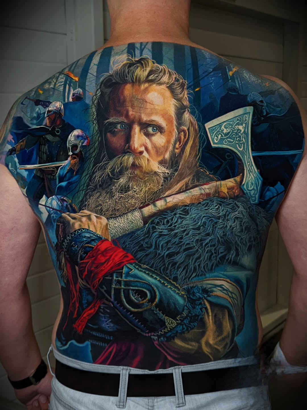 Vivid Norse warrior backpiece amid blue forest battle.