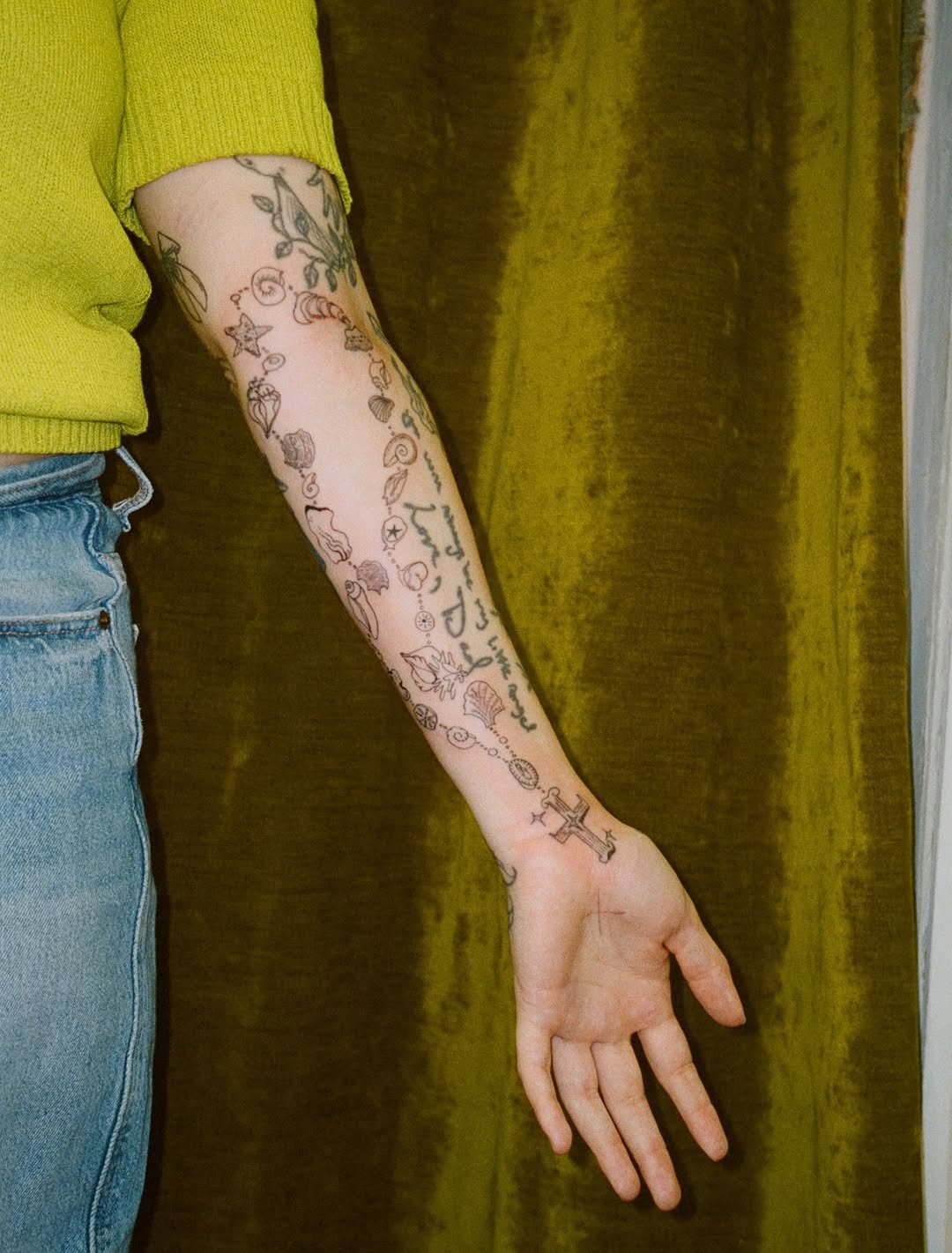 Shell rosary tattoo on arm