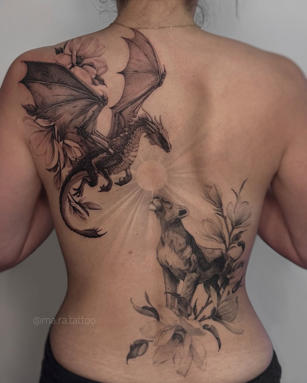 Majestic black-gray dragon with wings, sun halo, and blooming vines