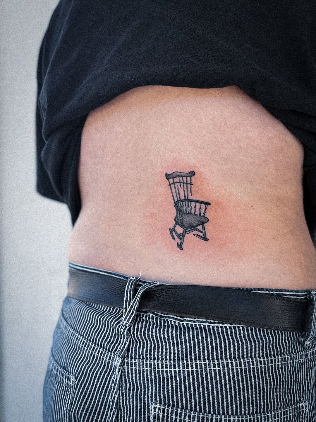 Small precise line-drawn rocking chair on side torso
