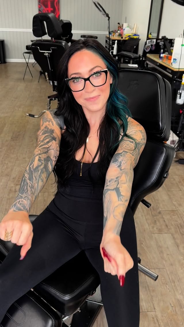 Bold black-and-gray sleeve tattoos across both arms
