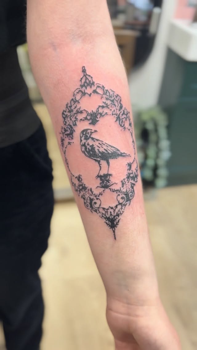 Delicate blackline bird inside ornate Victorian frame