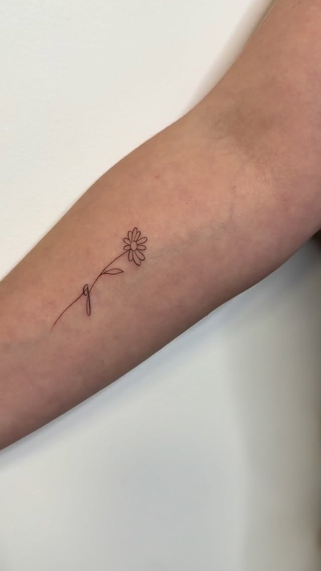 Delicate daisy fineline on the inner forearm.
