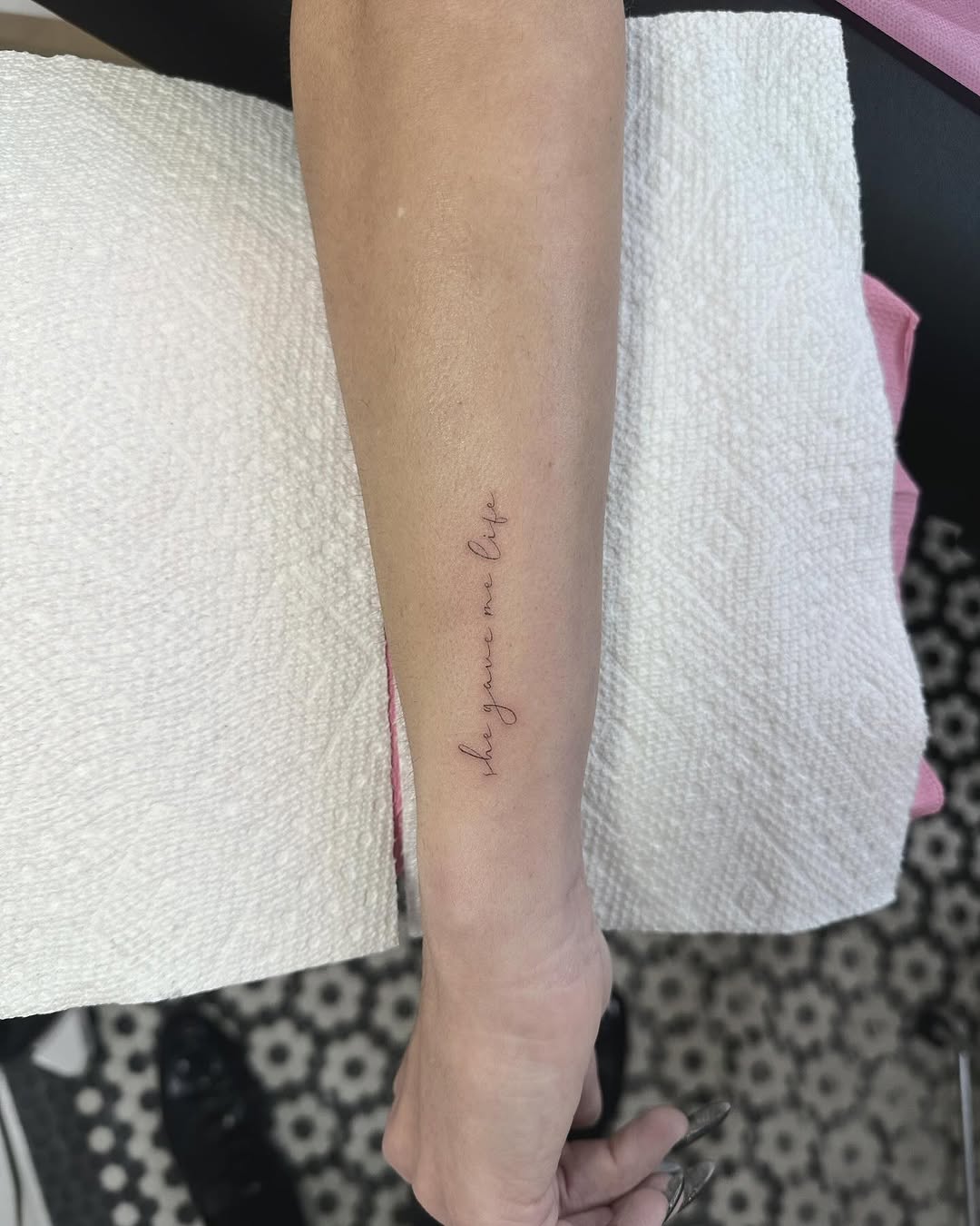 Delicate cursive script tattoo along the inner forearm
