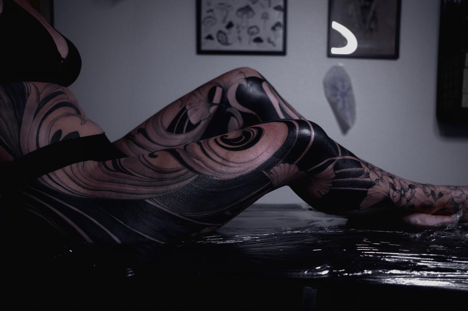 Dramatic blackwork with swirling waves across leg and forearm