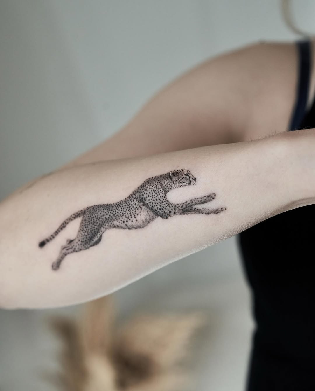 Leaping leopard rendered in fine-line dotwork on forearm