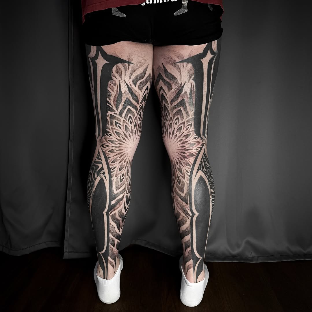 Striking blackwork leg sleeves with angular mandalas and negative-space shading.
