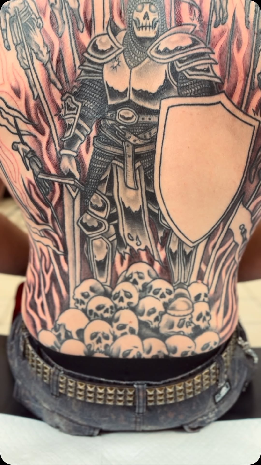 Dramatic black-and-gray knight portrait amid flames and skulls