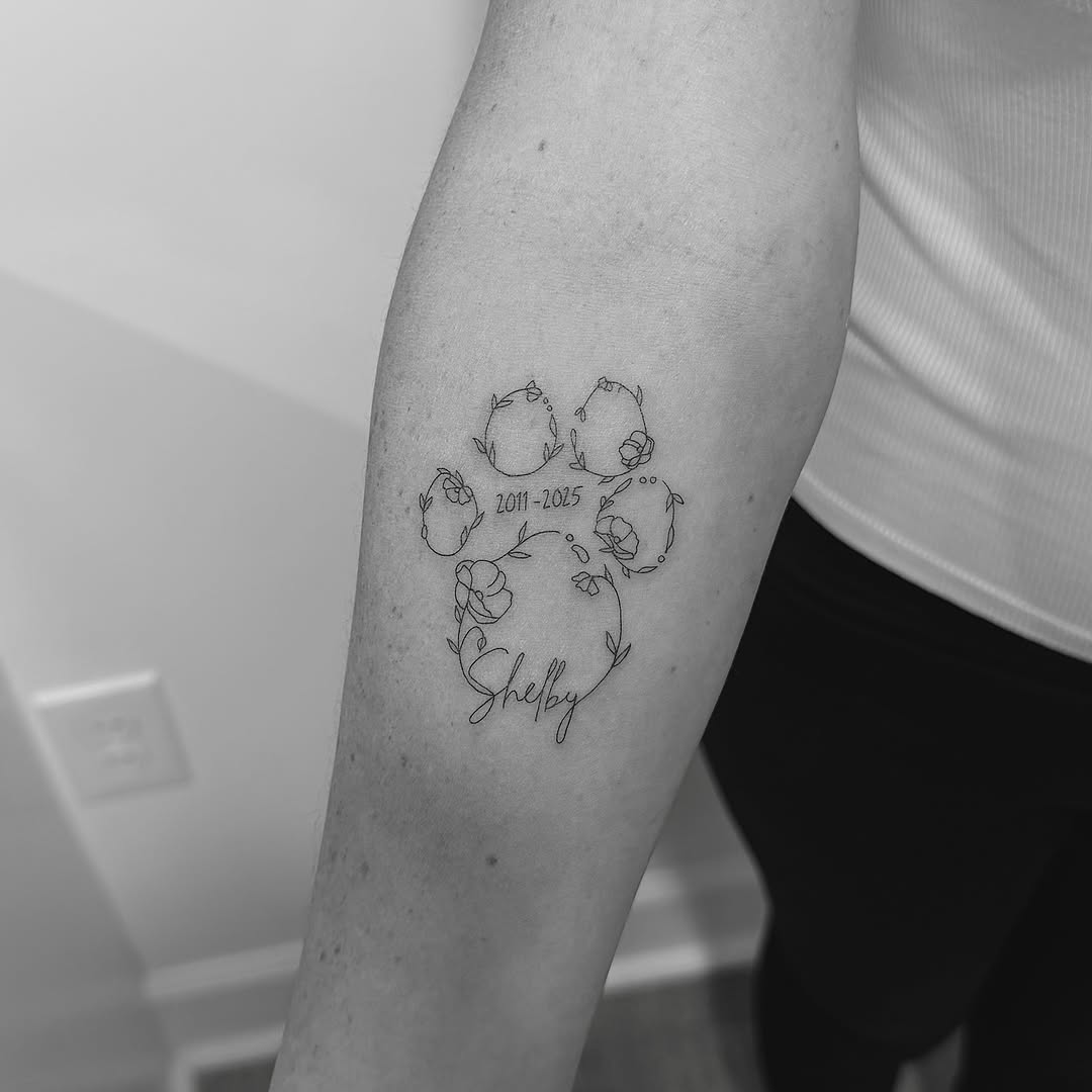 Delicate floral garland memorial tattoo with cursive Shelby.