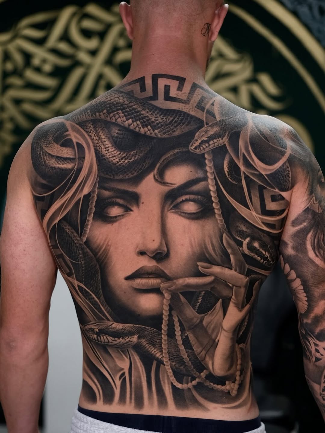 Hyper-detailed black-and-gray back piece portraying Medusa with coiling snakes