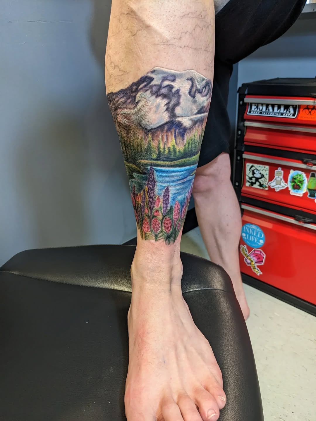 Vibrant mountain landscape leg tattoo with wildflowers