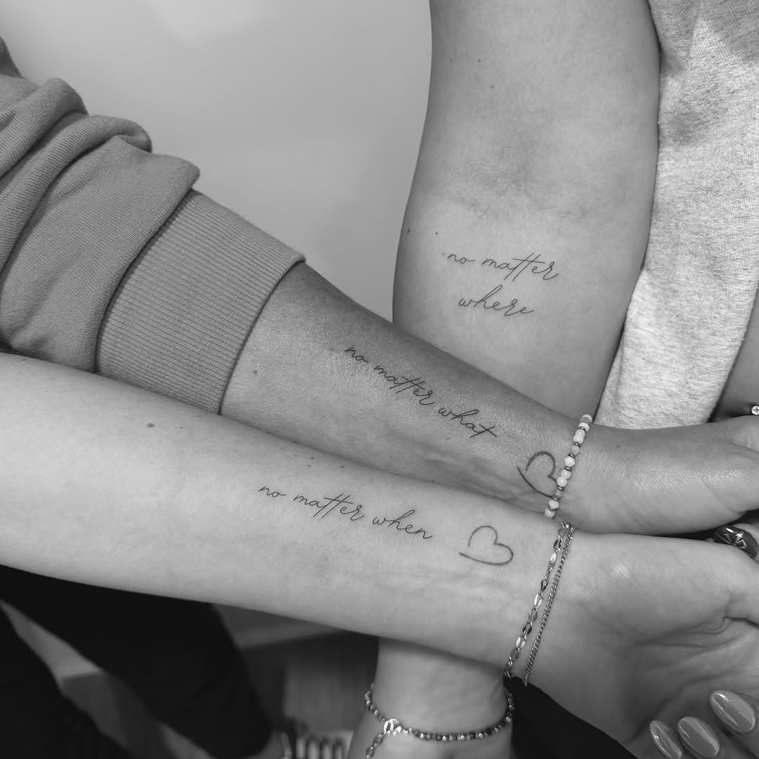 Delicate cursive script phrases tattooed on forearms.