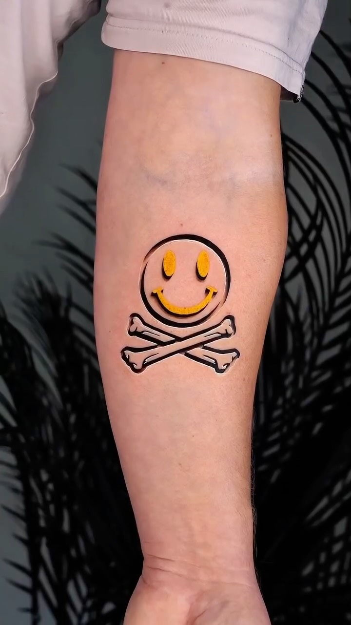 Playful yellow smiley circle with crossbones tattoo