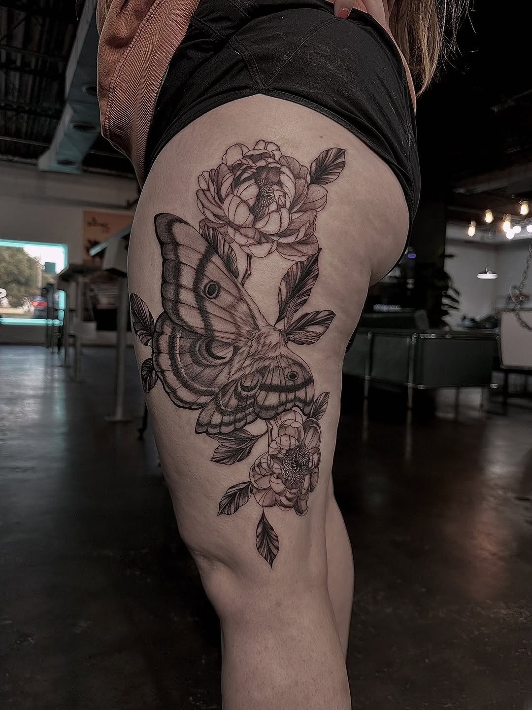 Bold black-and-gray moth entwined with lush peonies.