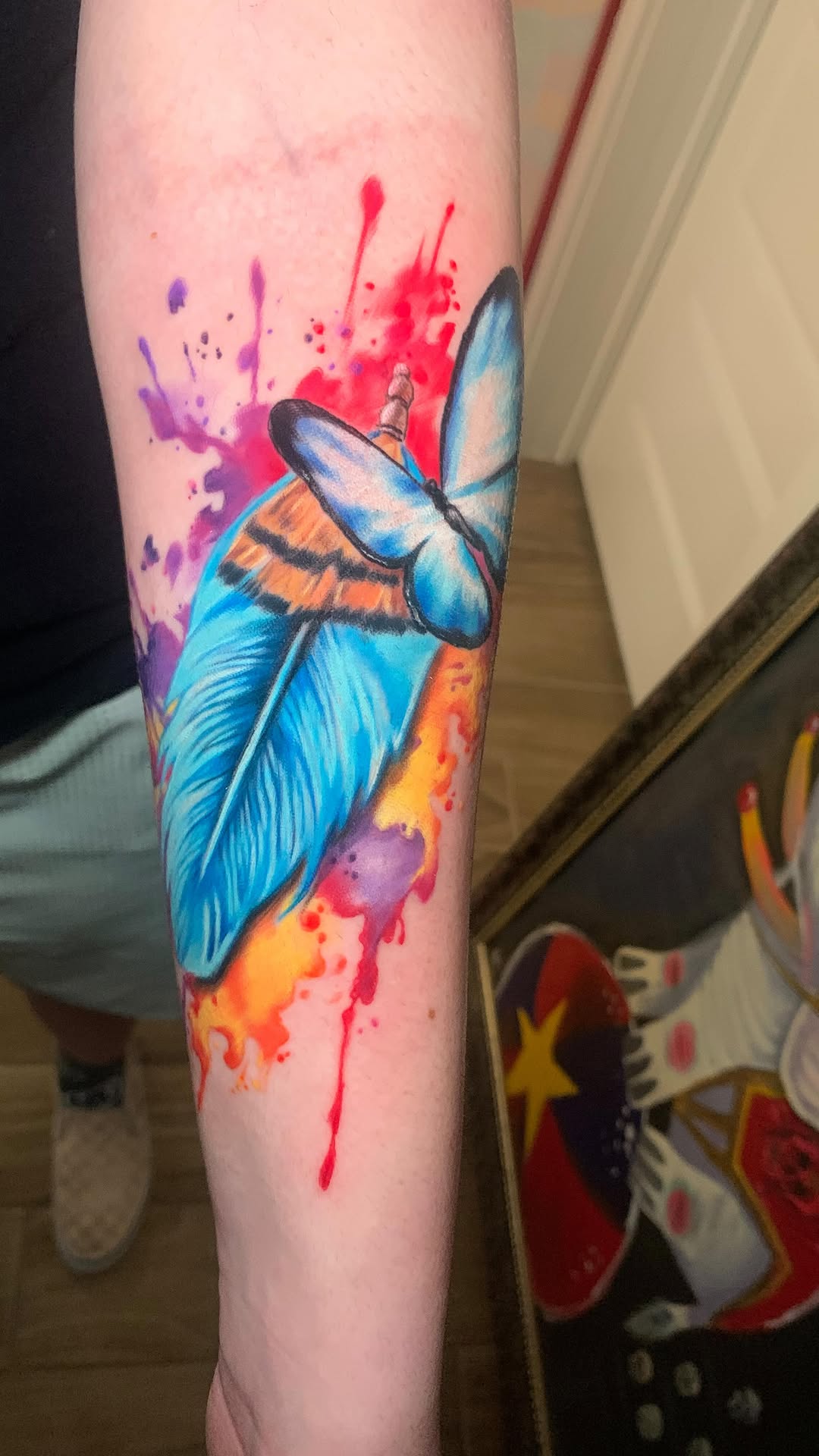 Vibrant watercolor feather tattoo with bold outlines