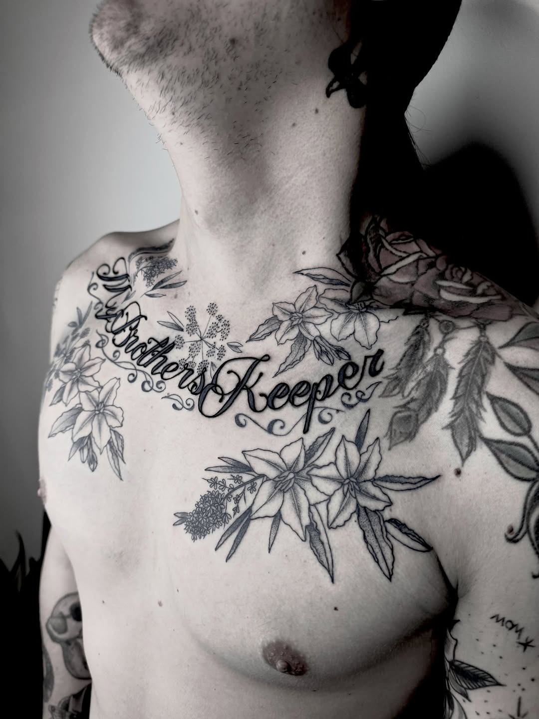 Curved script along collarbone with ornamental floral vines