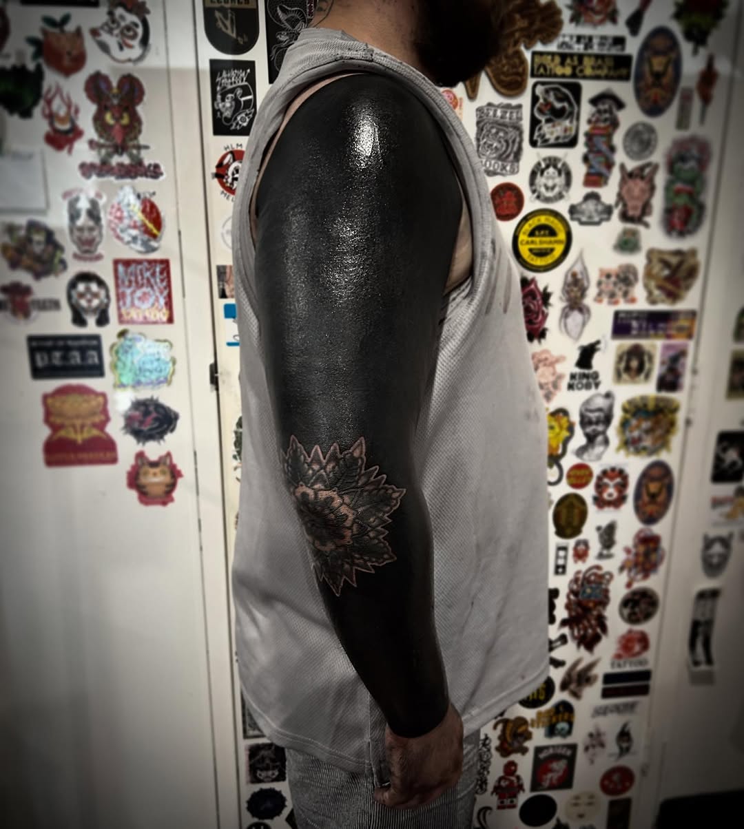 Bold all-black blackout sleeve with intricate negative-space lotus motif