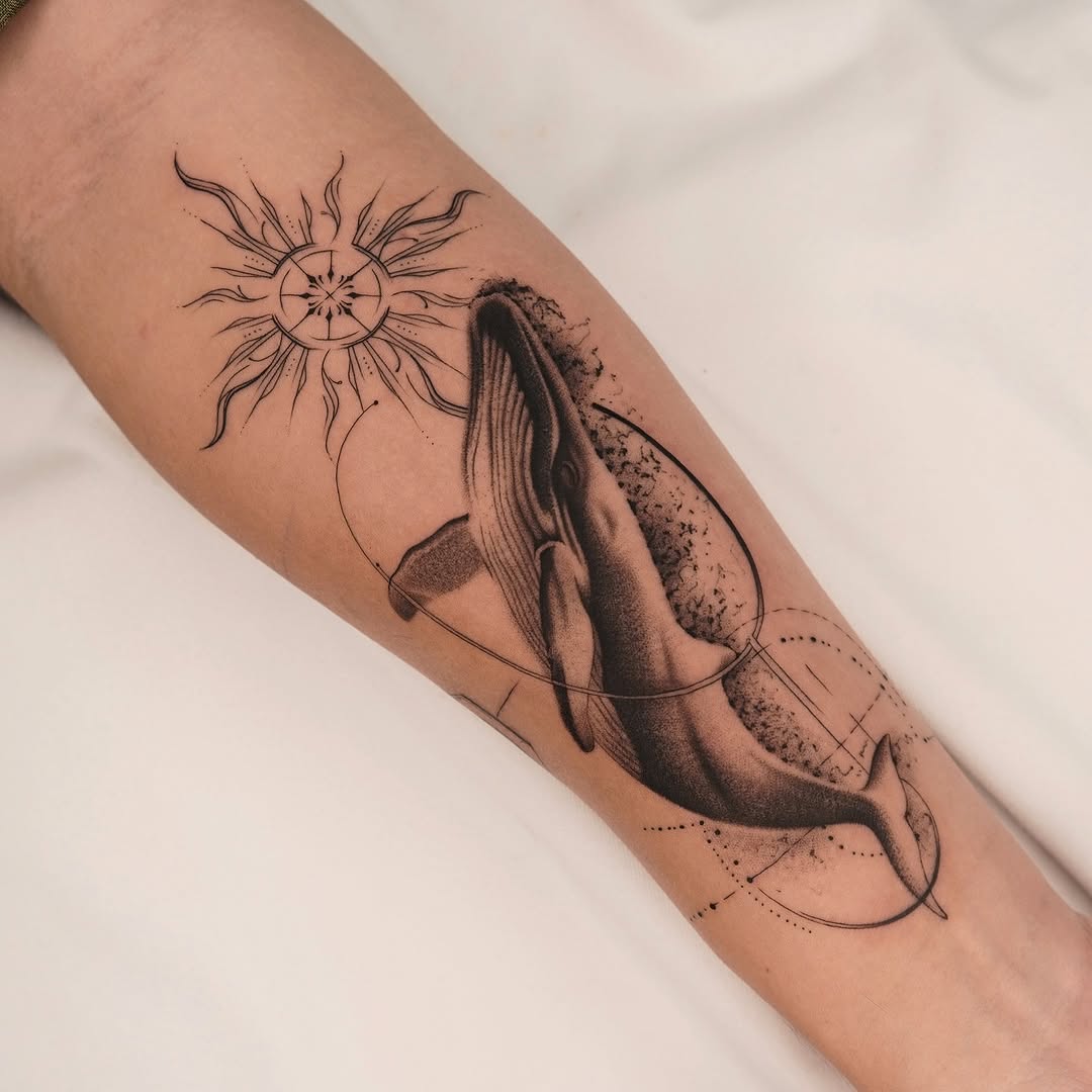 Geometric sunburst above a detailed whale-tail tattoo